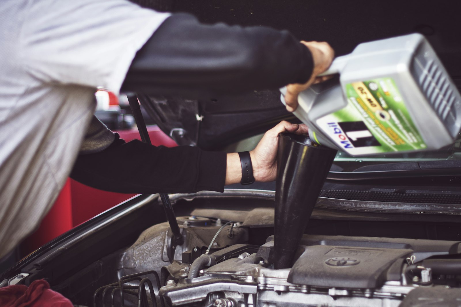 Mechanic pouring fresh motor oil into a car engine