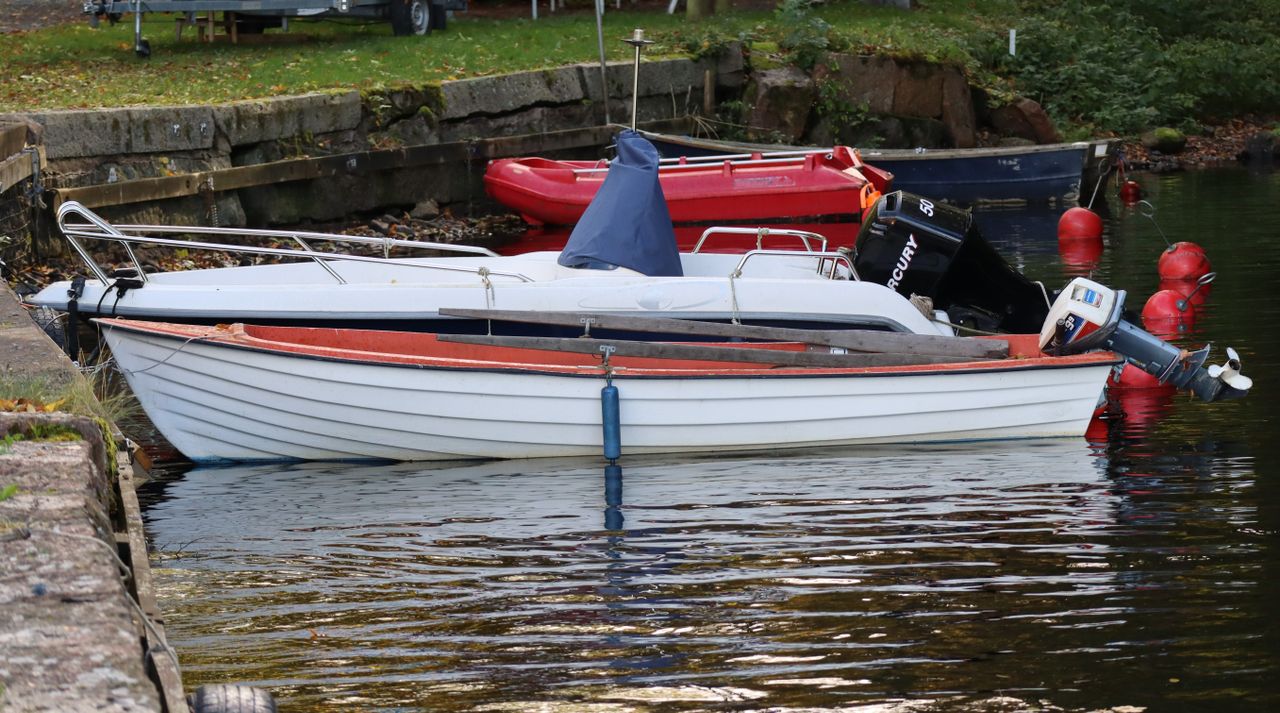 White motorboat with red trim docked at a marina, showing a Mercury outboard motor
