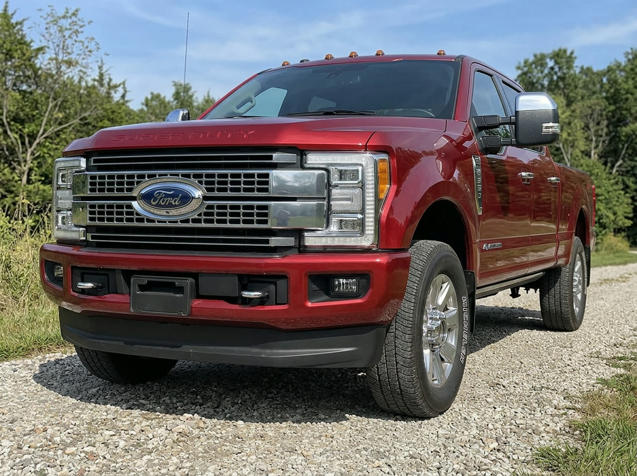 Red Ford F-250 Super Duty pickup truck parked on a gravel driveway